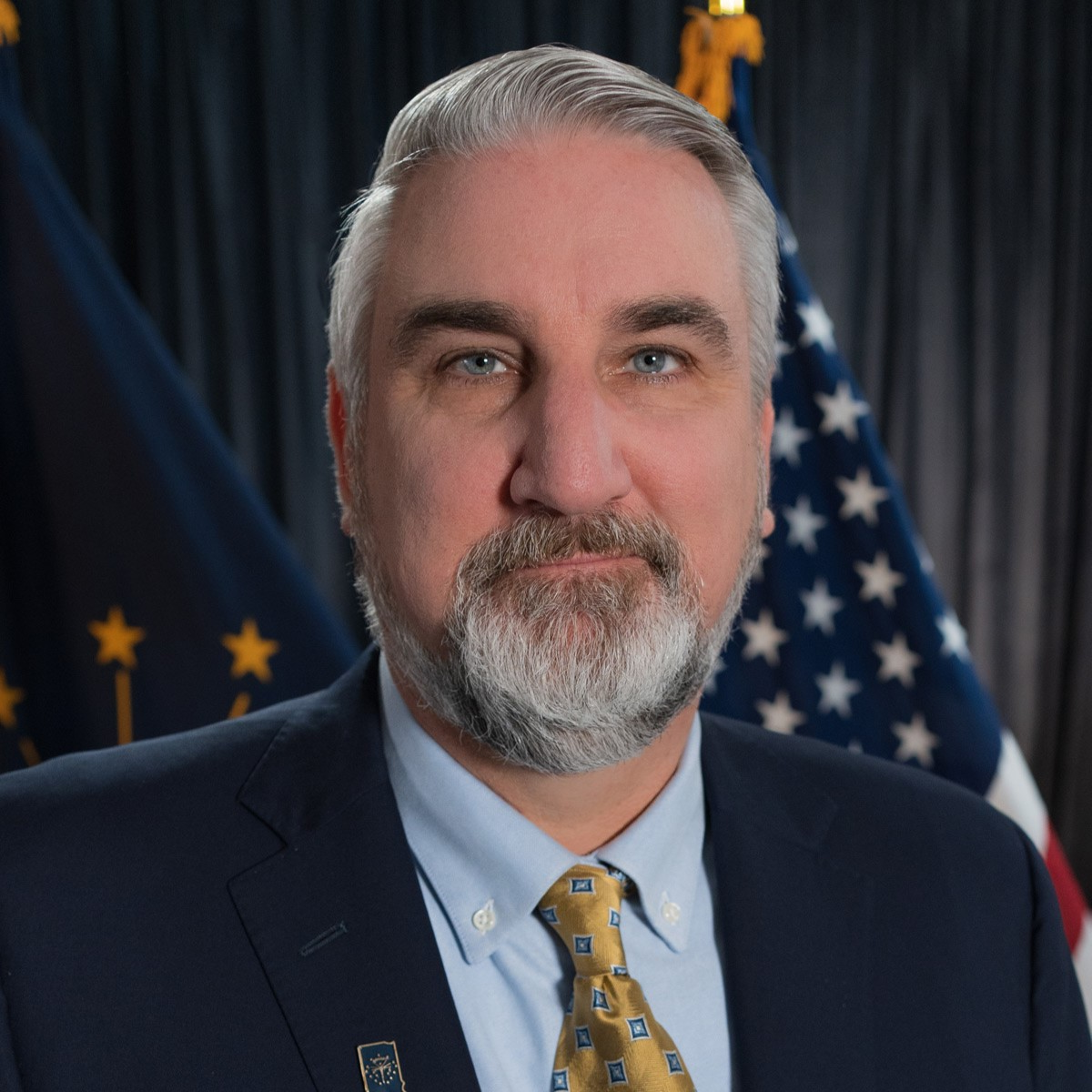 Eric Holcomb is wearing a suit and tie in his headshot. Indiana and American flags are in the background.